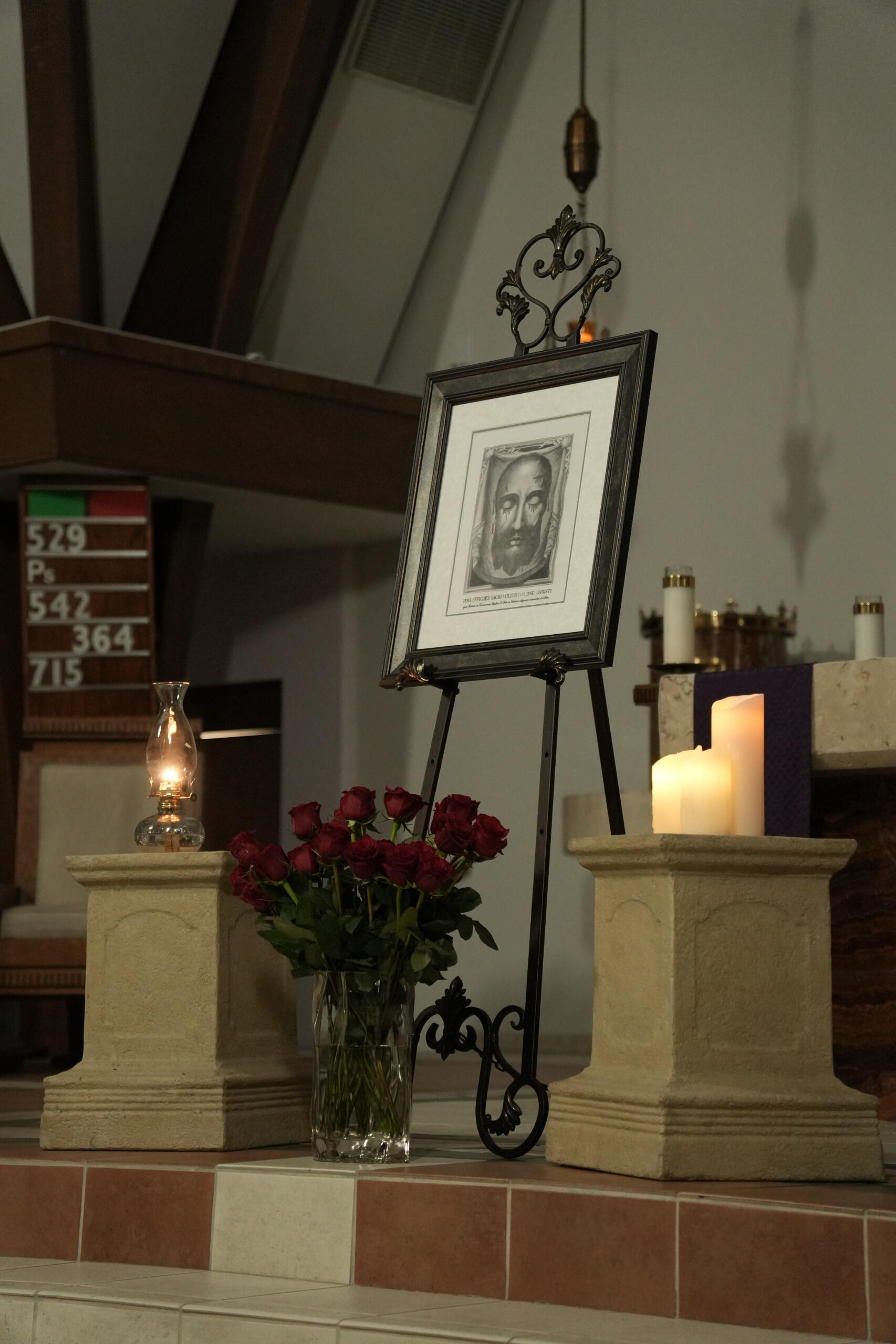 Photo of Holy Face relic in a picture frame with red roses in a vase